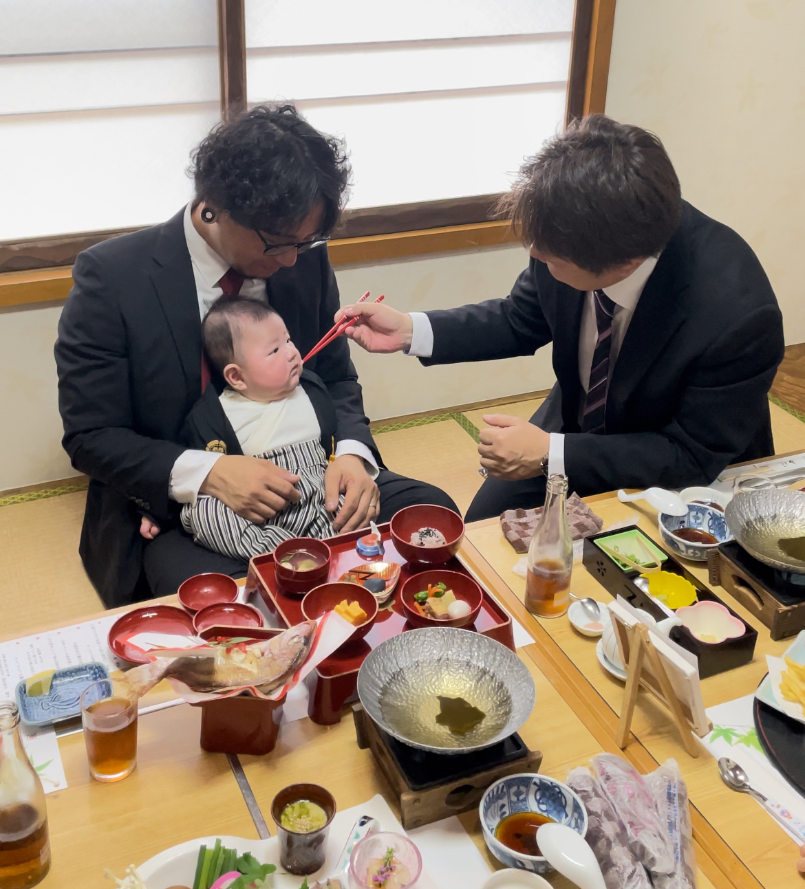 魚信の座敷で赤ちゃんを抱き、お食い初めを祝う様子