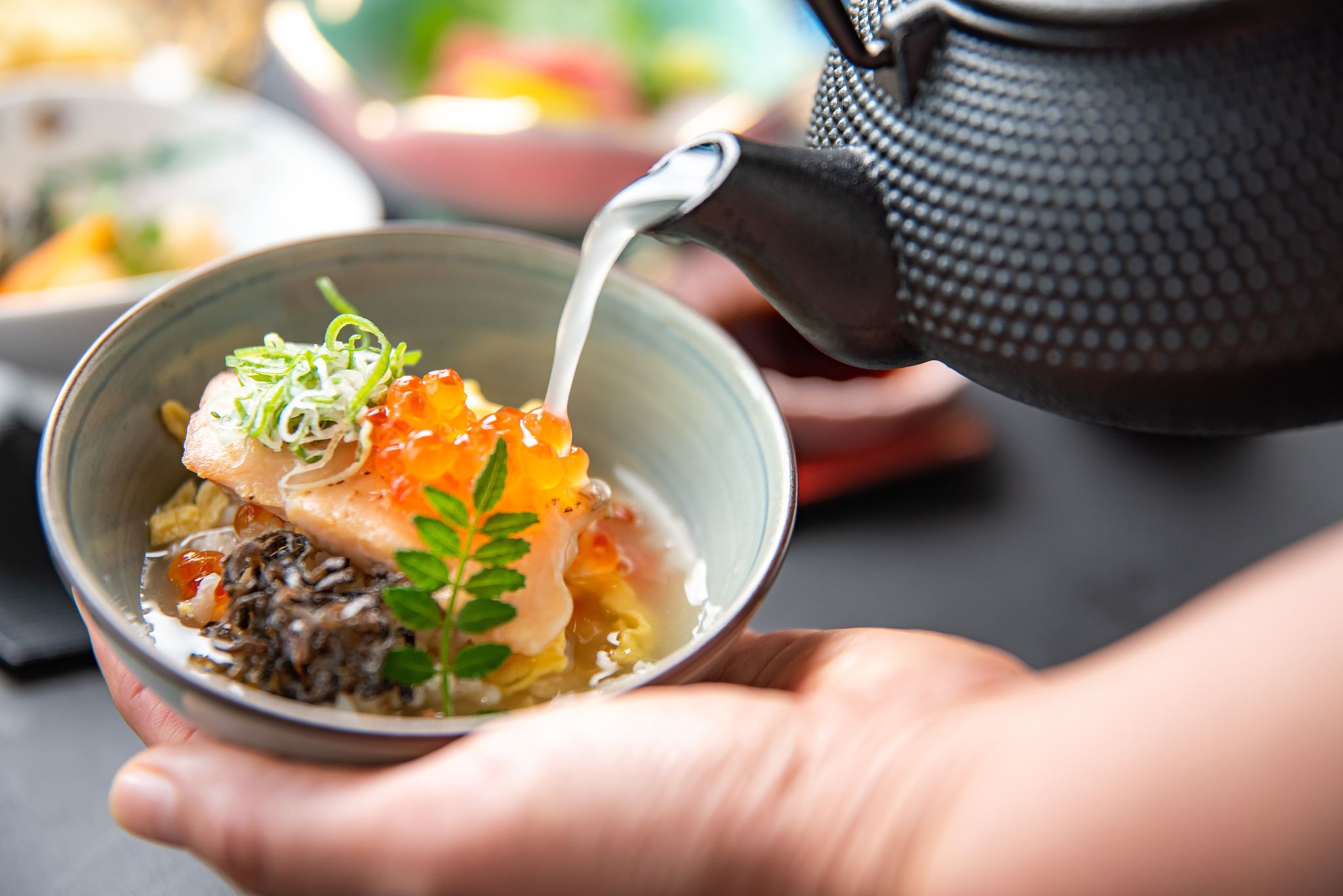 釜飯を茶碗によそい、出汁を注いでいる様子